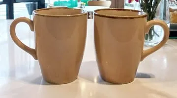Dos tazas de café en el local, con flores al fondo